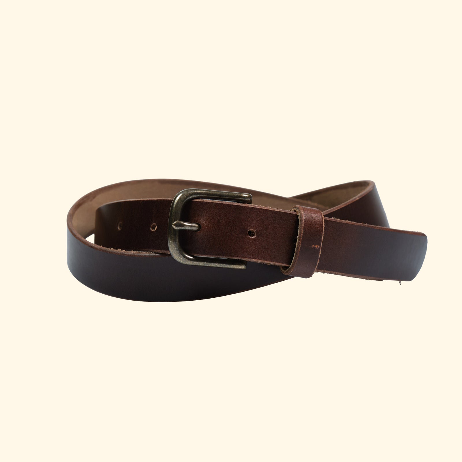 Schmaler Gürtel von oldpassion aus Horween Chromexcel in Dunkelbraun mit antique-farbener Dornschliesse und Lederschlaufe, leicht gedreht dargestellt.