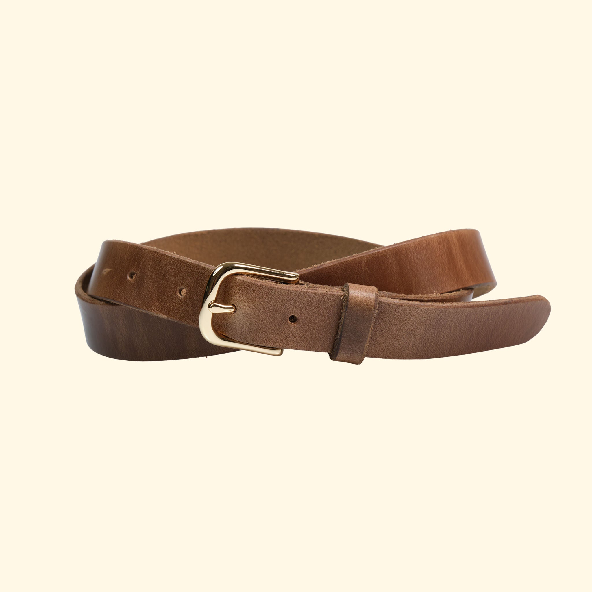 Schmaler Gürtel von oldpassion aus Horween Chromexcel in Natural mit goldfarbener Dornschliesse und Lederschlaufe, leicht gedreht dargestellt.