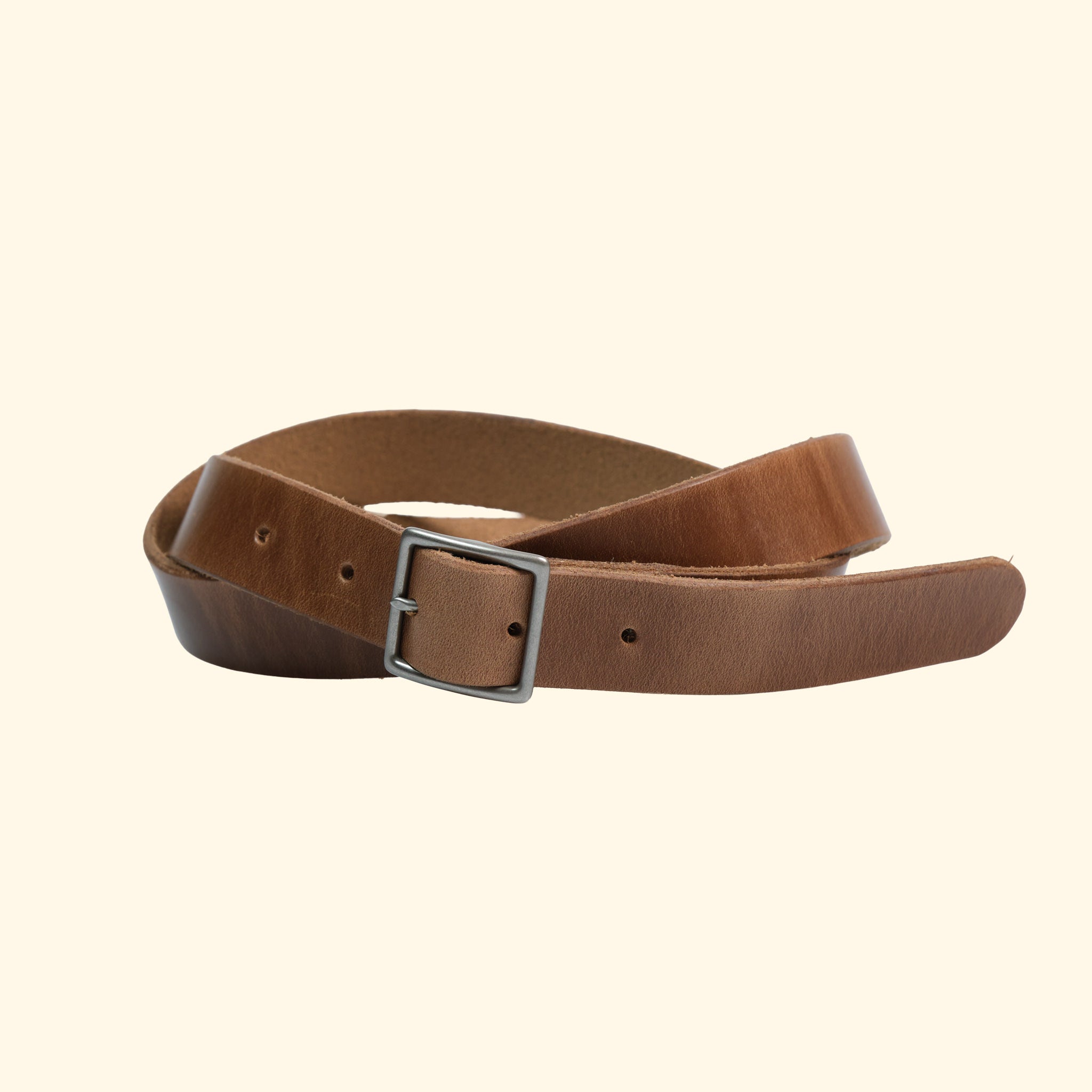 Schmaler Ledergürtel aus Horween Chromexcel in Natural mit antique-farbener Mittelsteg-Dornschliesse und Schlaufe, leicht gedreht dargestellt.