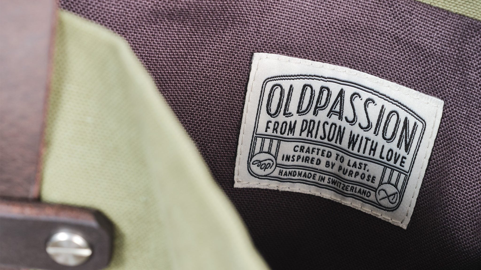 Eingewebte oldpassion-Etikette auf dem dunklen Futter der Canvas Tote Bag, daneben Canvas in Olive und ein Ledergriff