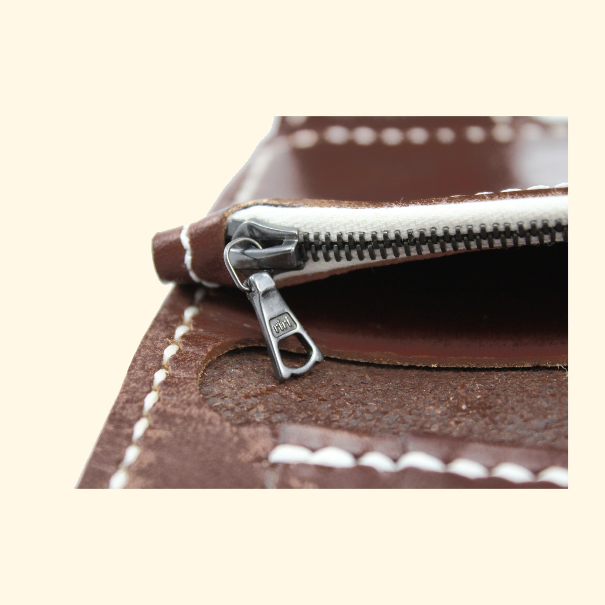 Detail des RIRI-Reissverschlusses am dunkelbraunen Oldpassion Snap Wallet mit rohweissem Band