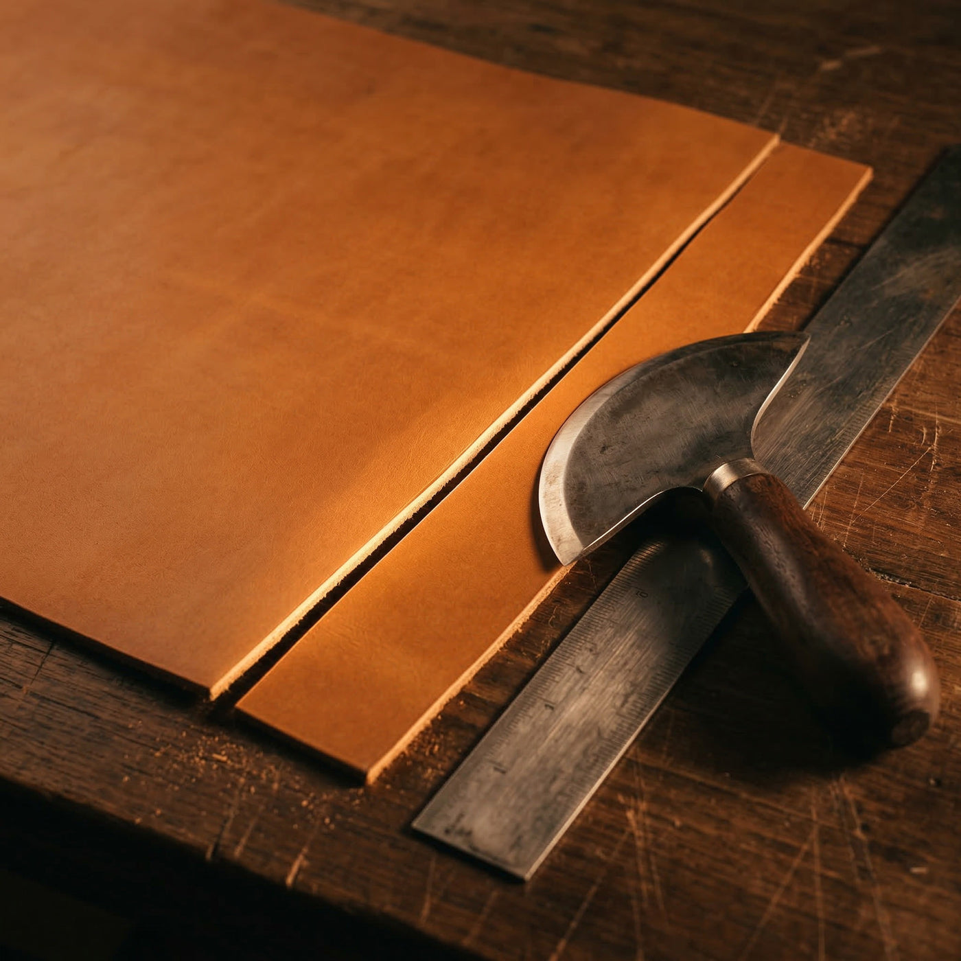 Vegetabil gegerbtes Full-Grain-Leder in Cognacton beim präzisen Zuschnitt auf einer Werkbank, das die ehrliche Materialqualität und traditionelle Handwerkskunst von oldpassion zeigt.