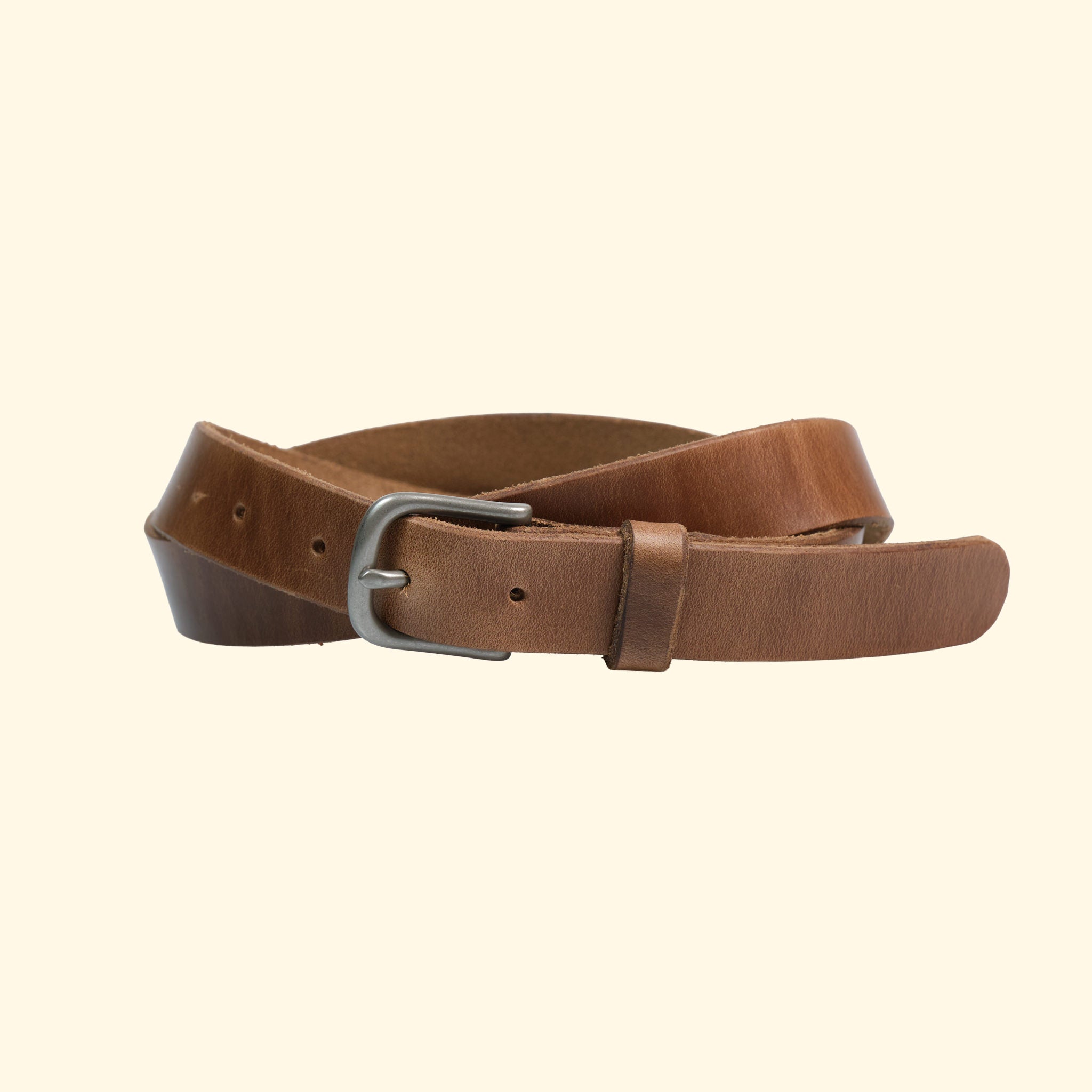 Schmaler Gürtel von oldpassion aus Horween Chromexcel in Natural mit silberfarbener Dornschliesse und Lederschlaufe, leicht gedreht dargestellt.