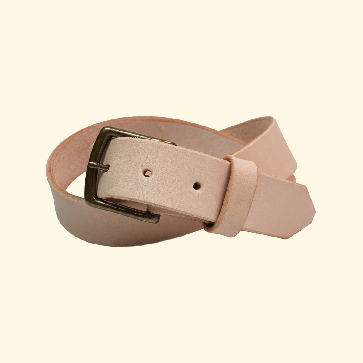 Handgefertigter Ledergürtel aus American Vachetta Leder in Naturfarbe, mit antiker Metallschnalle. Vorderansicht des gerollten Gürtels.